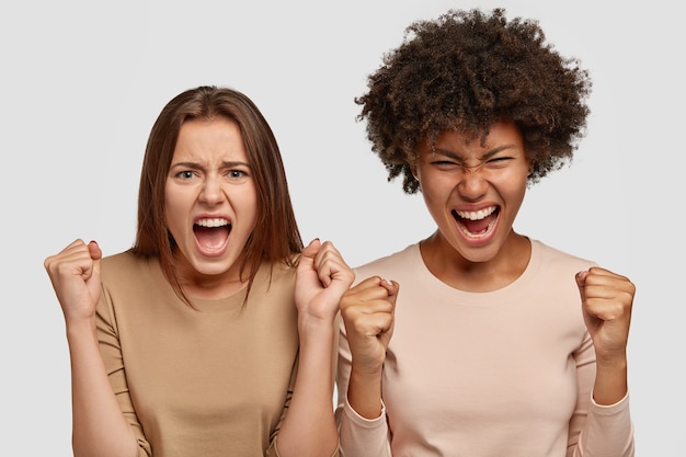 Empörte junge Frauen gemischter Rassen ballen die Fäuste