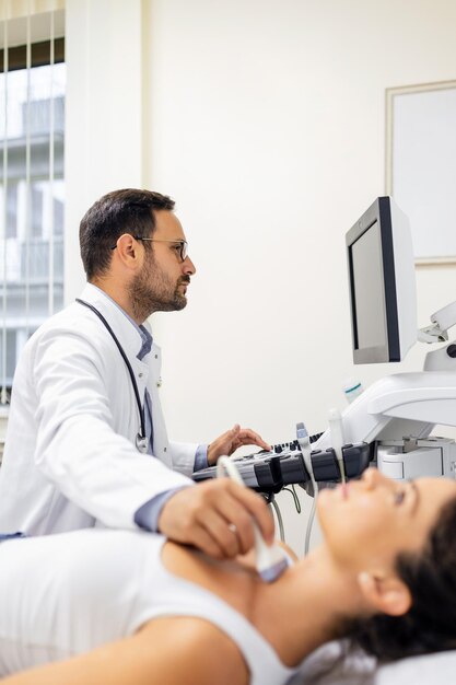 Endokrinologe, der einer Patientin in einem Ultraschallbüro eine Ultraschalluntersuchung macht Ultraschalldiagnostik der Schilddrüse