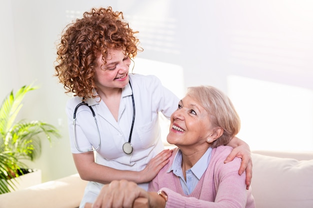 Enge positive beziehung zwischen älterem patienten und pflegekraft. glückliche ältere frau, die mit einer freundlichen pflegekraft spricht.