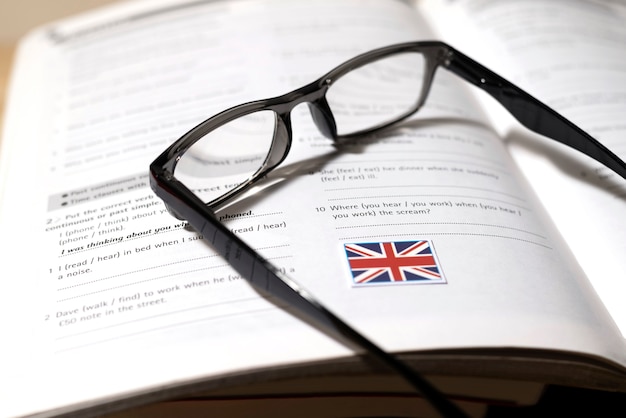 Englisches Buch mit Brille auf dem Tisch