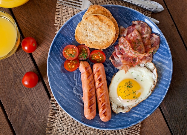 Englisches Frühstück - Toast, Ei, Speck und Gemüse im rustikalen Stil auf Holztisch