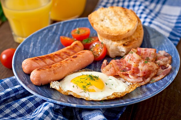 Englisches Frühstück - Toast, Ei, Speck und Gemüse im rustikalen Stil auf Holztisch