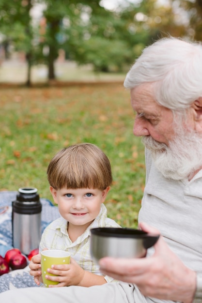 Enkel mit Großvater in trinkendem Tee des Parks