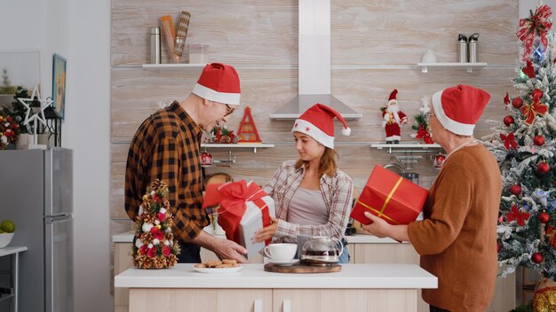 Enkelin bringt den Großeltern, die die Weihnachtszeit feiern, eine Geschenkverpackung mit Geschenküberraschung