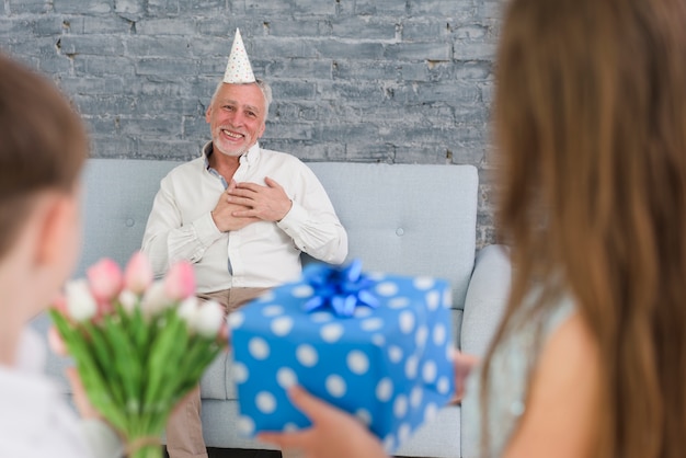 Kostenloses Foto enkelkinder, die ihrem überraschten großvater geschenke zeigen