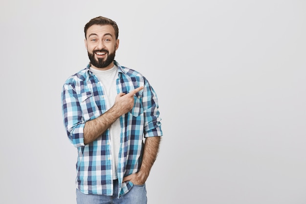 Enthusiastischer bärtiger Mann, der Finger rechts zeigt