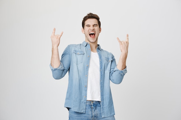 Enthusiastischer glücklicher Mann, der Spaß hat, zeigen Rock-n-Roll-Geste