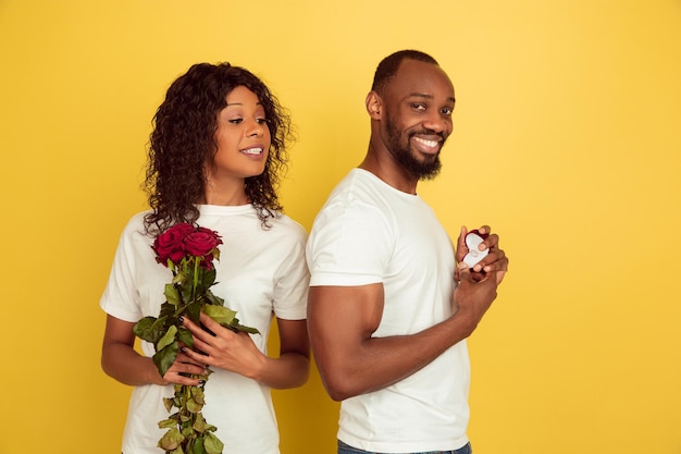 Entscheidung. Valentinstagfeier, glückliches Afroamerikanerpaar lokalisiert auf gelbem Studiohintergrund.