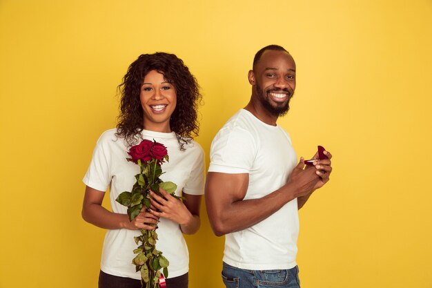 Entscheidung. Valentinstagfeier, glückliches afroamerikanisches Paar lokalisiert auf gelber Wand. Konzept der menschlichen Gefühle, Gesichtsausdruck, Liebe, Beziehungen, romantische Feiertage.