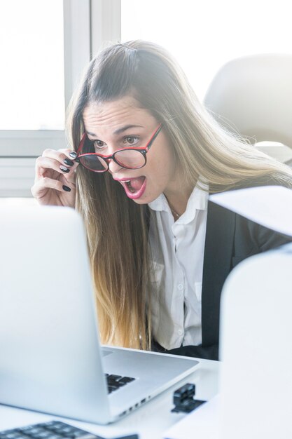 Entsetzte junge Geschäftsfrau, die Laptop betrachtet