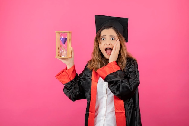 Kostenloses Foto entsetzte schöne studentin, die zeituhr hält, legte ihre hand zu ihrem gesicht. foto in hoher qualität