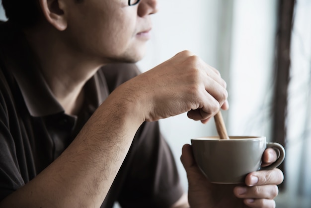 Entspannen Sie sich den asiatischen Mann, der einen Kaffee trinkt