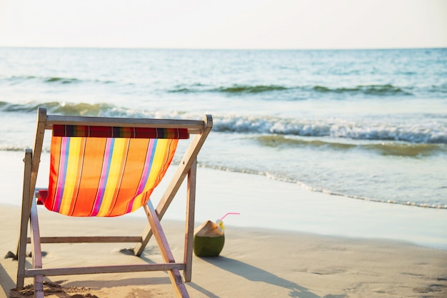 Entspannen Sie sich Strandstuhl mit frischer Kokosnuss auf sauberem Sandstrand mit blauem Meer und klarem Himmel - Seenatur entspannen sich Konzept