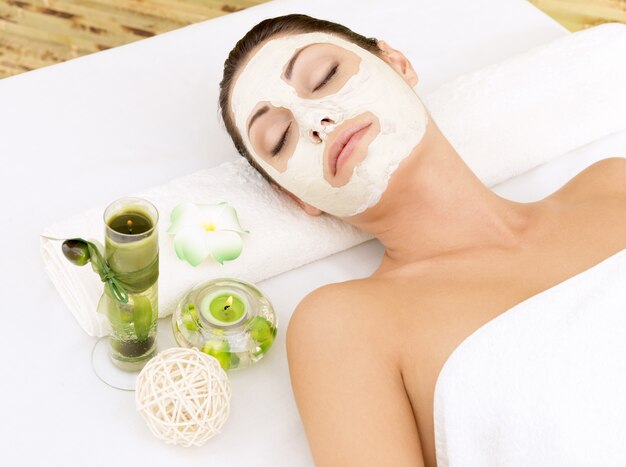 Entspannende Frau am Spa-Salon mit kosmetischer Maske auf Gesicht.