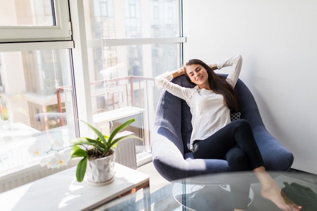 Kostenloses Foto entspannende frau, die bequem im sofa-liegestuhl zu hause sitzt