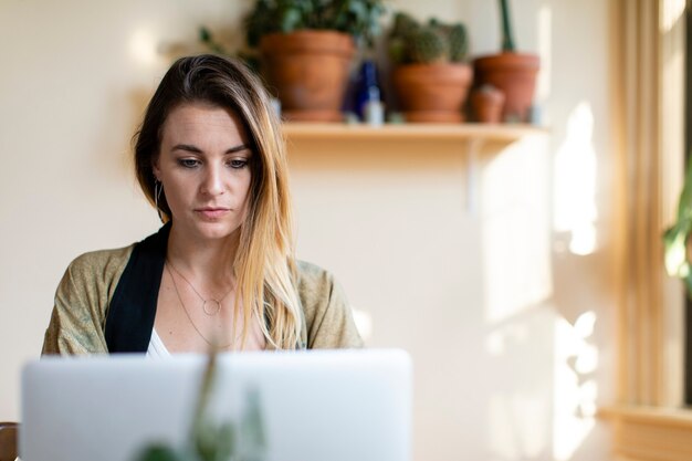 Entspannte Frau, die von zu Hause aus an ihrem Laptop arbeitet