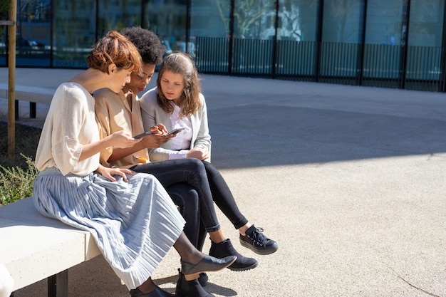 Entspannte Frauen mit Smartphones sprechen auf der Straße