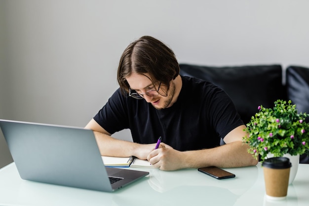 Entspannter Mann, der in einem modernen Büro arbeitet und auf der Tastatur auf einem bequemen Stuhl sitzt