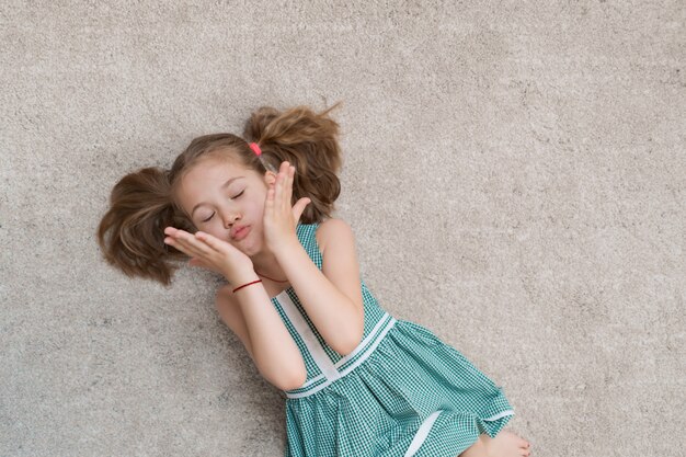Entspanntes kleines Mädchen, das drinnen auf dem Boden liegt und lächelt
