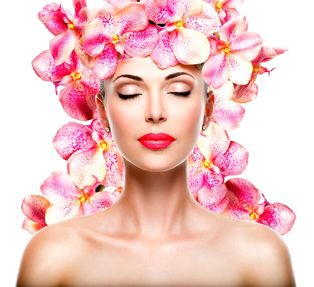 Entspanntes schönes Gesicht eines jungen Mädchens mit klarer Haut und rosa Orchideen. Schönheitsbehandlungskonzept