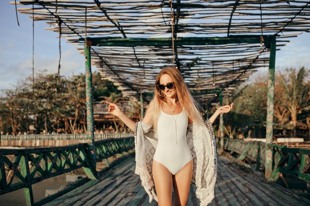 Entzückende europäische Frau, die mit Lächeln auf Natur tanzt. Elegante gebräunte Dame in der Sonnenbrille, die Glück am Sommerresort am Wochenende ausdrückt.