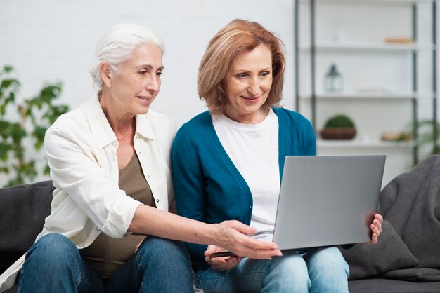 Entzückende fällige Frauen, die einen Laptop verwenden