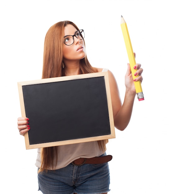 Entzückende junge frau mit tafel und großen bleistift