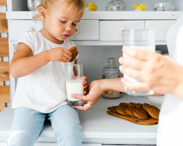 Entzückende Tochter, die Plätzchen mit Milch isst