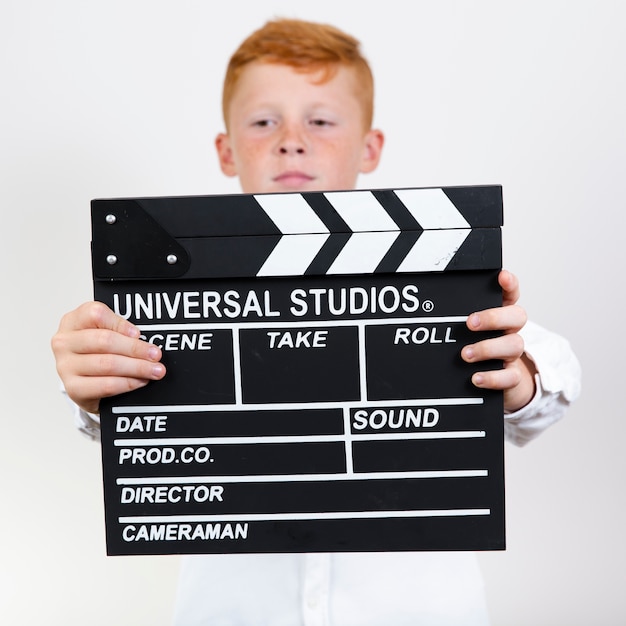 Kostenloses Foto entzückender junge, der clapperboard hält