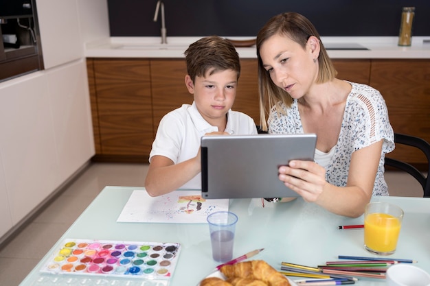 Kostenloses Foto entzückender junge, der tablette mit mutter prüft