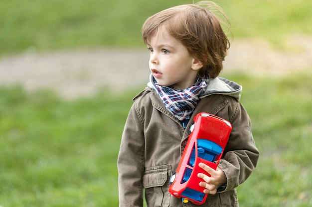 Entzückender Junge mit dem Spielzeugauto, das weg schaut