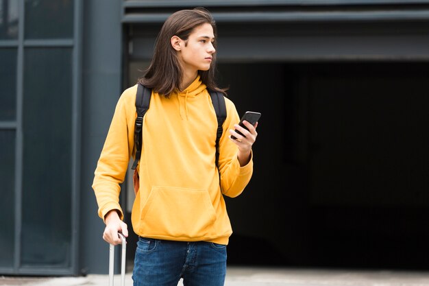 Entzückender junger Reisender, der sein Telefon hält