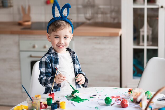 Entzückender kleiner Junge, der Eier für Ostern malt