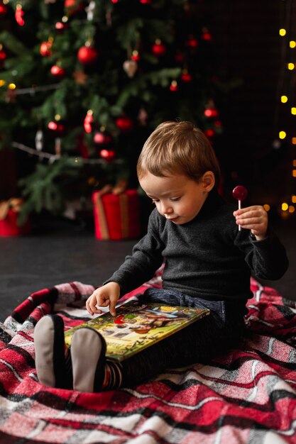 Entzückender kleiner Junge, der mit Weihnachtsspielzeug spielt