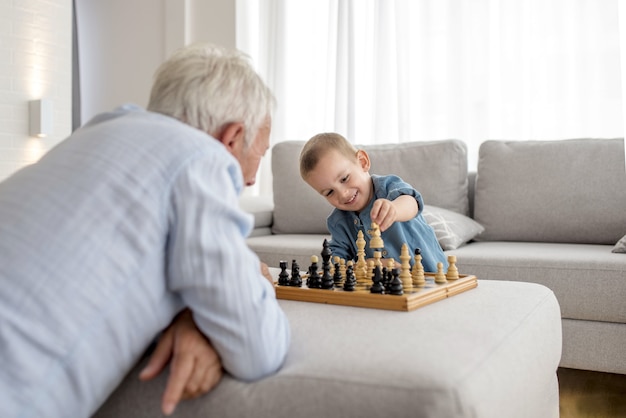 Entzückender kleiner Junge, der Schach mit seinem Großvater spielt