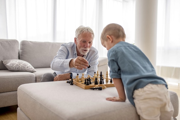 Entzückender kleiner Junge, der Schach mit seinem Großvater spielt