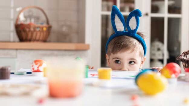 Entzückender kleiner Junge mit Hasenohren, die sich verstecken