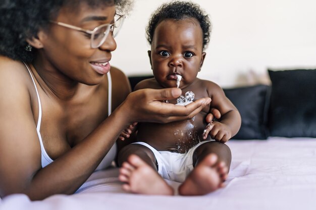 Entzückendes afroamerikanisches Baby, das Milch in der Hand ihrer Mutter erbricht