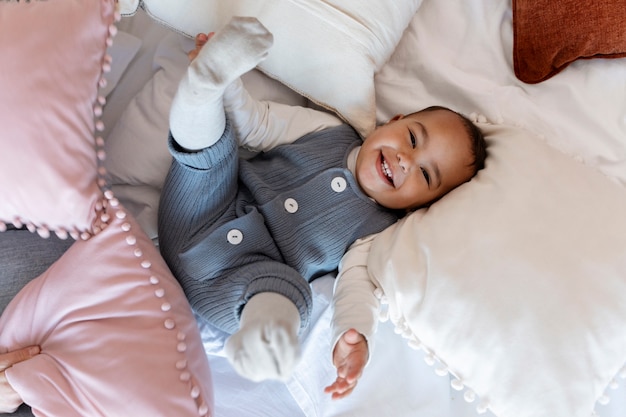 Entzückendes Baby, das auf Bett lacht und legt
