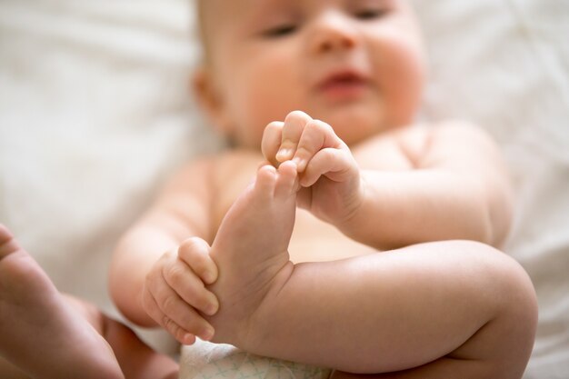 Entzückendes Baby, das ein Interesse an seinen Füßen hat