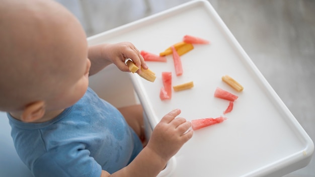 Entzückendes Baby, das mit Essen spielt