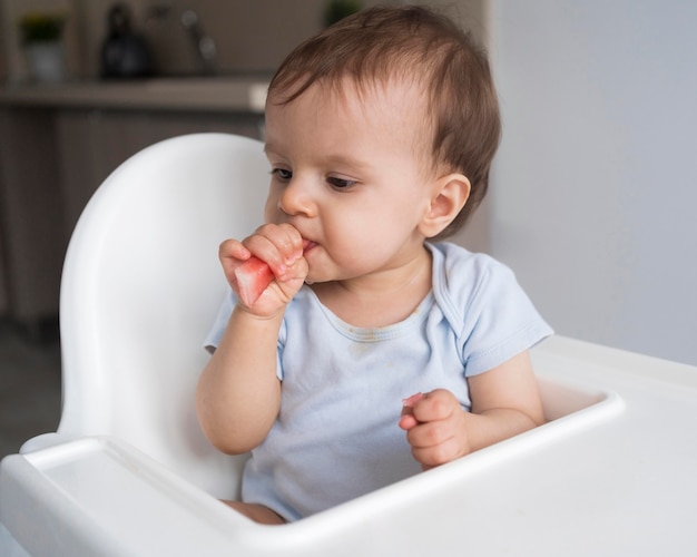 Entzückendes Baby, das mit Essen spielt