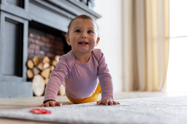 Entzückendes Baby, das zu Hause mit Spielzeug auf dem Boden spielt