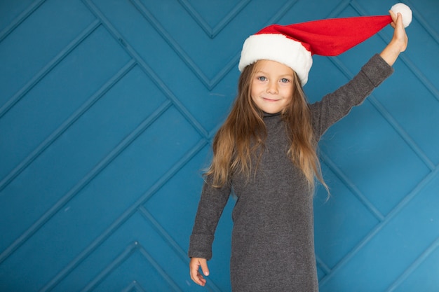 Entzückendes blondes Mädchen, das einen Weihnachtsmann-Hut trägt