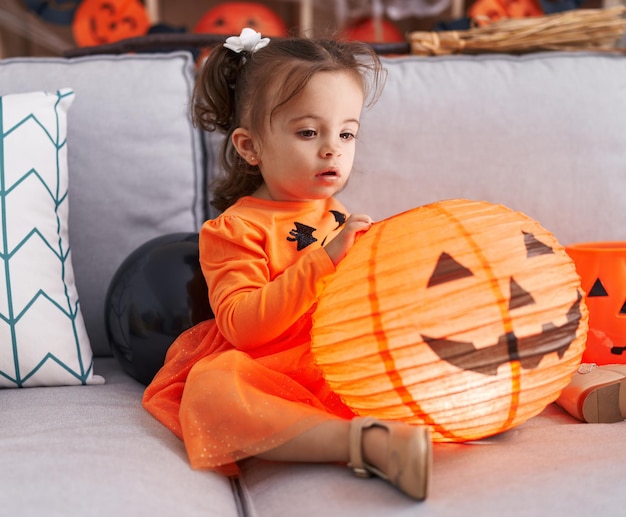 Kostenloses Foto entzückendes hispanisches kleinkind, das halloween-party hat, das kürbisspielzeug zu hause hält