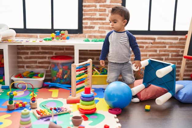 Entzückendes hispanisches Kleinkind, das mit ernster Miene im Kindergarten steht