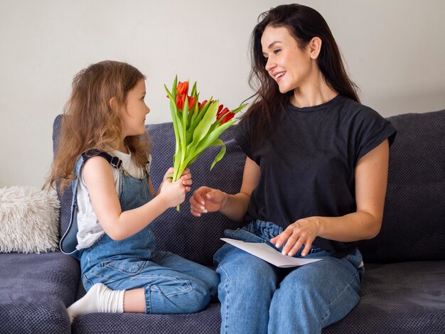 Entzückendes junges Mädchen, das der Mutter Blumen gibt