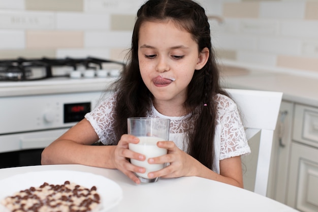 Entzückendes junges Mädchen, das ein Milchglas hält