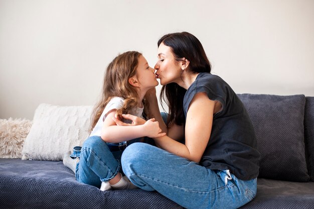 Entzückendes junges Mädchen, das ihre Mutter küsst