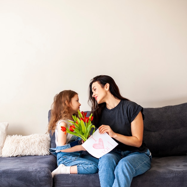 Kostenloses Foto entzückendes junges mädchen, das ihrer mutter blumen gibt